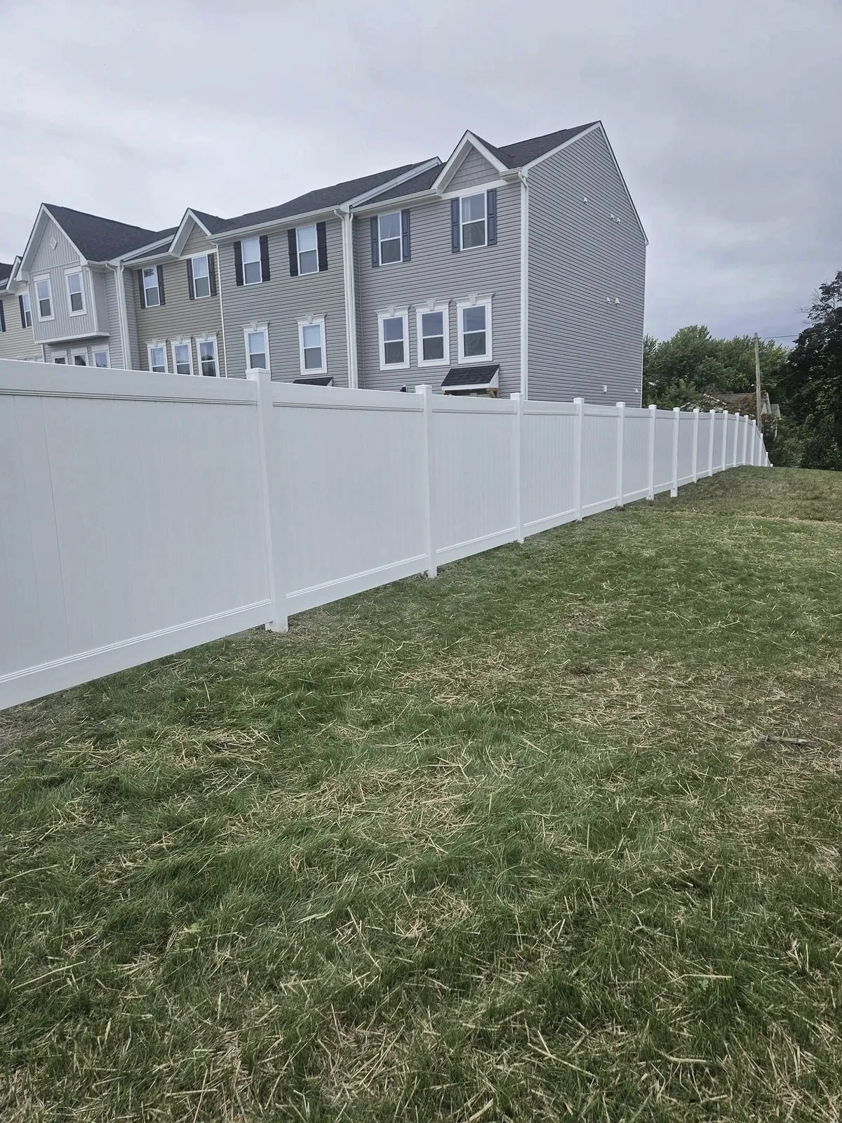 clean-lines-white-fence-grassy-area-next-to-houses-on-cloudy-day